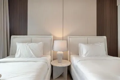 two beds with white sheets and a table with a lamp at Luxury 4BR Burj Khalifa View Dubai Mall in Dubai