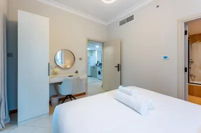 a white bedroom with a white bed and a desk at Prestigious 2BR with nice View of Marina Dubai in Dubai