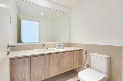 a bathroom with a toilet and a sink and a mirror at Luxury Modern Home with Direct Park Access in Dubai