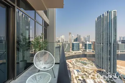 a balcony with two chairs and a view of a city at Bespoke Holiday Homes - Elegant 2BR Waterfront Stay with Canal View in Dubai