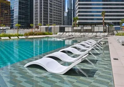 a row of white lounge chairs next to a swimming pool at Bespoke Holiday Homes - Elegant 2BR Waterfront Stay with Canal View in Dubai