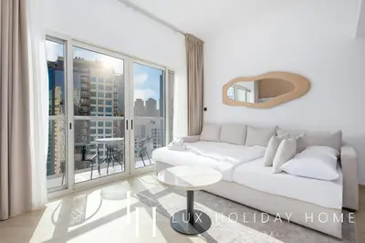 a living room with a white couch and a large window at LUX The Marina View Suite 3 in Dubai
