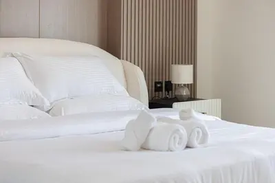a white bed with two towels on top of it at Stylish Family Retreat That Sleeps 6 In The Heart of JVC in Dubai