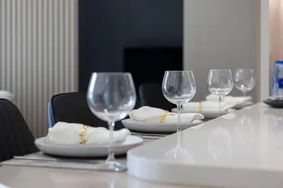 four wine glasses sitting on a table with plates at Stylish Family Retreat That Sleeps 6 In The Heart of JVC in Dubai