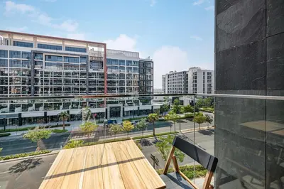 a balcony with a wooden table and some buildings at Daniels Studio at Meydan with Community View in Dubai