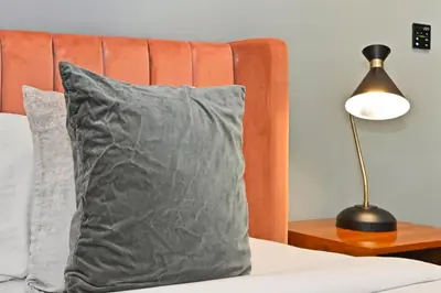 a bed with a grey pillow and a lamp at Relax in Comfort with Modern Amenities, Steps from Burj Khalifa and Dubai Mall in Dubai