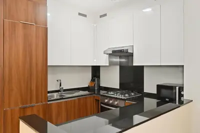 a kitchen with white cabinets and a black counter top at Relax in Comfort with Modern Amenities, Steps from Burj Khalifa and Dubai Mall in Dubai