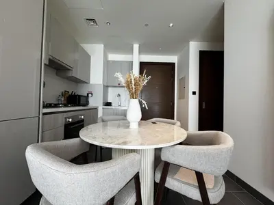 a kitchen with a table with chairs and a vase with flowers at Luxury 1-Bedroom Apartment with Pool Access in DIFC, Dubai in Dubai