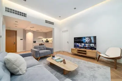 a living room with a couch and a tv at Newly Refurbished Luxury Garden Apartment with Burj Khalifa View and Direct Pool Access in Downtown Dubai in Dubai