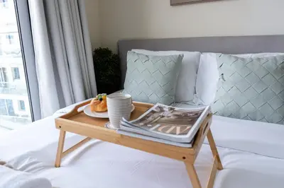 a tray with a plate of food on a bed at Modern Studio with Balcony, Stunning City Views & Free Parking, Close to Dubai Mall in Dubai