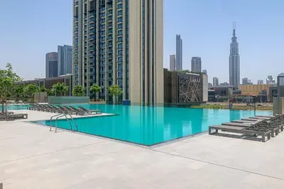 a large swimming pool with chairs and a building at Brand New 1BR, Downtown View, 5 Min Dubai Mall in Dubai