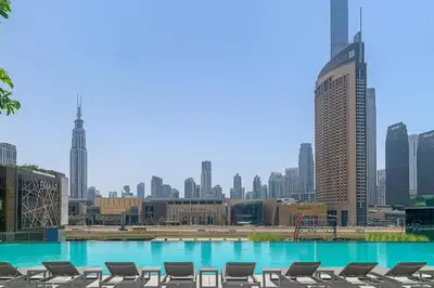 a large swimming pool with chairs in a city at Brand New 1BR, Downtown View, 5 Min Dubai Mall in Dubai
