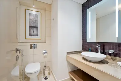 a bathroom with a sink and a toilet and a mirror at High-Rise Living - Paramount Tower - 1 bedroom in Dubai