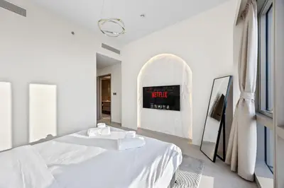 a white bedroom with a bed and a clock on the wall at Elegant High-Rise Escape with sea view by SoleaStay in Dubai