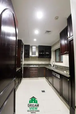 a kitchen with brown cabinets and a white tile floor at Souk Al Bahar View Burj Khalifa and Fountains Dream View Holiday Homes in Dubai