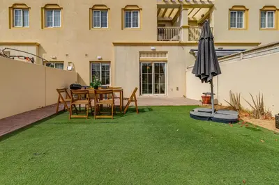 a patio with a table and an umbrella and grass at The Springs 8 - 2 Bedroom with Maids Room Villa - Allsopp & Allsopp in Dubai