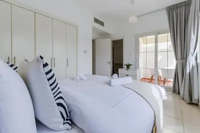 a white bedroom with a large white bed with pillows at The Springs 8 - 2 Bedroom with Maids Room Villa - Allsopp & Allsopp in Dubai
