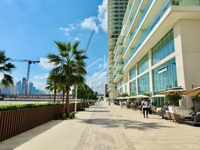 a sidewalk in front of a building with palm trees at Cozy 1BD Apartment in Grand Bleu, Emaar Beachfront in Dubai