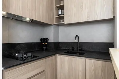 a kitchen with wooden cabinets and a sink at Maison Privee - Serene Studio Escape with Balcony in JVC in Dubai