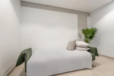 a white room with a white bed and a plant at GuestReady - 2BR City View | Canal | High Floor in Dubai