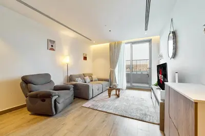 a living room with a couch and a chair at 1BR with Huge Terrace & Pool View at JVC in Dubai