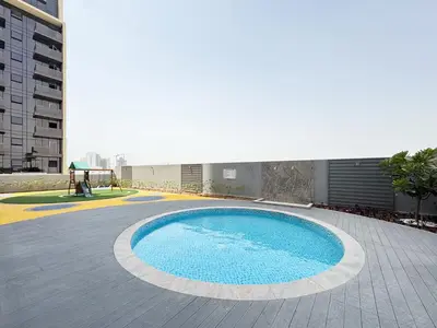 a large swimming pool in the middle of a building at 1BR with Huge Terrace & Pool View at JVC in Dubai