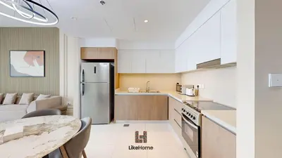 a kitchen with a stainless steel refrigerator and a table at Grand Apartment -3 Bedrooms in Dubai