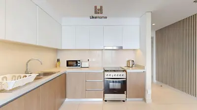 a kitchen with white cabinets and a stove top oven at Grand Apartment -3 Bedrooms in Dubai
