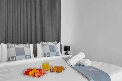 a bed with a tray of fruit and drinks on it at Direct Burj & Fountain Views - Designer 4BR Haven! in Dubai