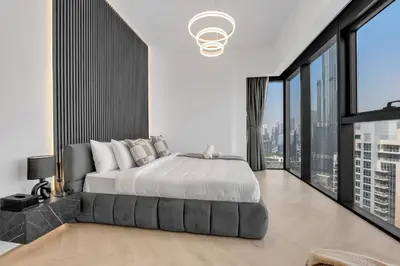a bedroom with a large bed and large windows at Direct Burj & Fountain Views - Designer 4BR Haven! in Dubai