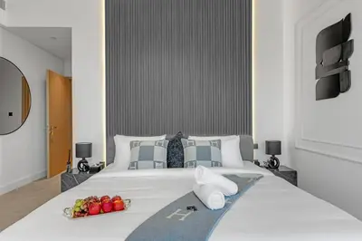 a large white bed with a tray of fruit on it at Direct Burj & Fountain Views - Designer 4BR Haven! in Dubai