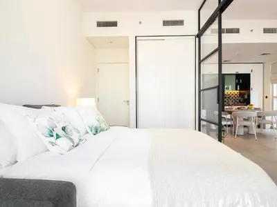 a bedroom with a large white bed and a dining room at Modern & Stylish Stay in 1BR Socio Dubai Hills in Dubai