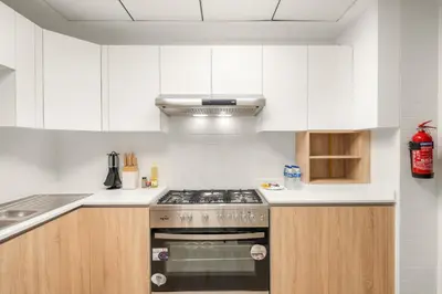 a kitchen with white cabinets and a stove top oven at Cozy 2BR with Canal View & Partial Burj View in Dubai
