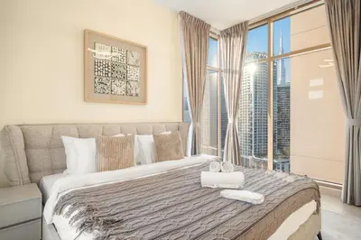 a bedroom with a large bed with a window at Cozy 2BR with Canal View & Partial Burj View in Dubai