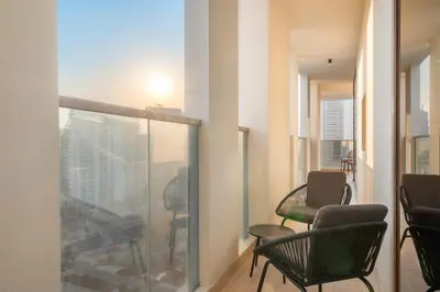 a room with chairs and a balcony with a view at Cozy 2BR with Canal View & Partial Burj View in Dubai