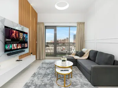 a living room with a couch and a tv at Stylish 1BR Near Burj Khalifa with Rooftop Pool, City Views, Free Parking in Dubai