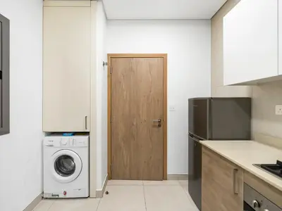 a kitchen with a washing machine and a wooden door at Stylish 1BR Near Burj Khalifa with Rooftop Pool, City Views, Free Parking in Dubai