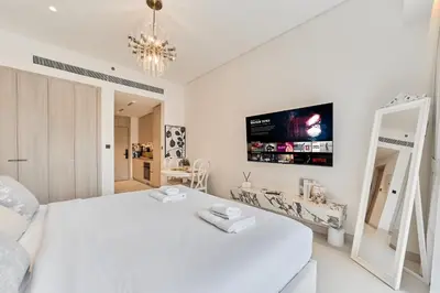 a white bedroom with a white bed and a tv at Bright Studio Retreat in Floarea Residence Arjan in Dubai