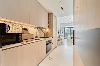 a kitchen with white cabinets and a stove top oven at Bright Studio Retreat in Floarea Residence Arjan in Dubai