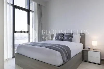 a bedroom with a large bed and a large window at Bloomfieilds Spacious 1br Azizi Fawad in Dubai