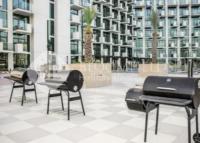 two bbq fires on a patio in front of a building at Bloomfieilds Spacious 1br Azizi Fawad in Dubai