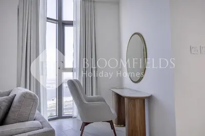 a living room with a chair and a mirror at Bloomfieilds Spacious 1br Azizi Fawad in Dubai