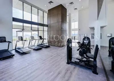 a gym with treadmills and cardio equipment in a room at Bloomfieilds Spacious 1br Azizi Fawad in Dubai