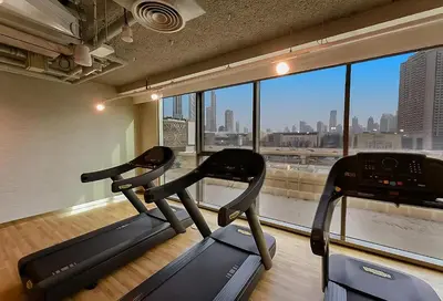 a gym with two exercise machines and a large window at Modern 1BR Near Dubai Mall in Downtown Views II in Dubai