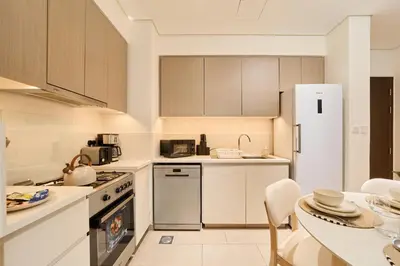 a kitchen with a white refrigerator and a table at Your Dubai Hills Retreat 1BR in Park Heights 2 in Dubai
