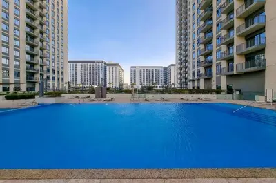 a large blue swimming pool in the middle of two apartment buildings at Your Dubai Hills Retreat 1BR in Park Heights 2 in Dubai