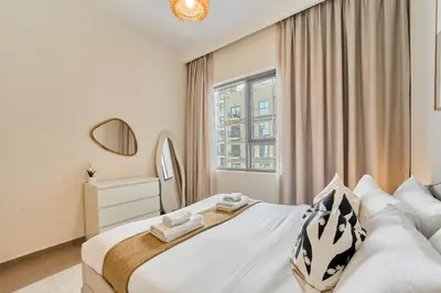 a white bedroom with a large bed and a window at Your Dubai Hills Retreat 1BR in Park Heights 2 in Dubai