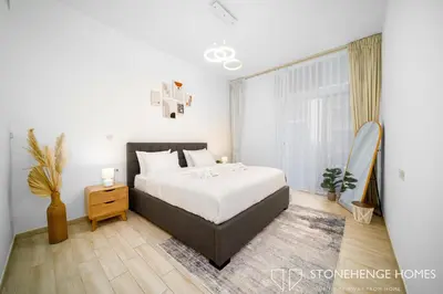 a bedroom with a bed and a large window at Cozy 1BR in Belgravia , JVC, Pool View, 20 Min from Downtown Dubai in Dubai