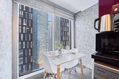 a kitchen with a white table and a large window at Twisting Tower Stay a Chic 2BR in Cayan Tower in Dubai