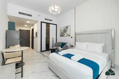 a bedroom with a large white bed and a table at Peaceful Studio in Opalz by Danube by BMS in Dubai